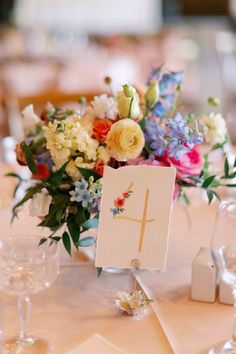 a table topped with a vase filled with flowers and a cross on top of it