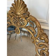 an ornate gold mirror in the middle of a room with chairs and tables behind it