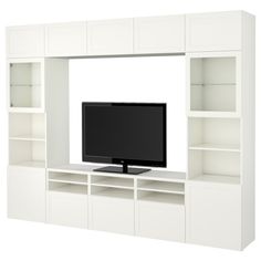 a flat screen tv sitting on top of a white entertainment center with built - in shelving