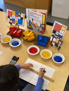 a young child is painting on paper at a table with legos and other toys