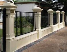 an iron fence and gate in front of a white house with black wrought iron fencing