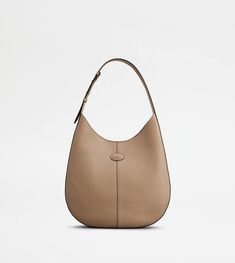 The timeless elegance of the Di Bag style is declined in a hobo version with sober and essential lines. Crafted in fine natural grain calfskin leather, it comes with an adjustable shoulder handle and the characteristic Tod's logo stamped on the front. Complemented by a removable internal pouch, it accompanies your everyday outfits with class and femininity. Beige Bag, Gift Boutique, Bag Style, Logo Stamp, Trainers Women, Bago, Light Beige, Everyday Outfits, Leather Shoulder Bag