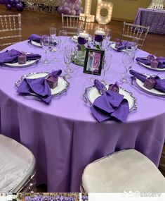 the table is set with purple cloths and place settings