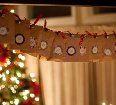 a decorated christmas tree with candles in the foreground and small brown bags hanging from it's sides