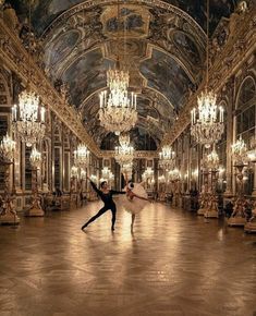 two ballerinas in an ornate ballroom with chandeliers