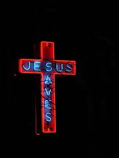 a cross lit up in the dark with jesus saves us