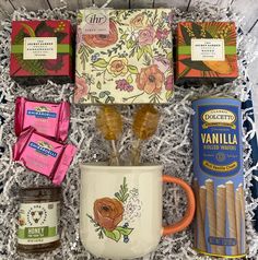 an assortment of items in a gift box including candles, coffee mug and candy bars