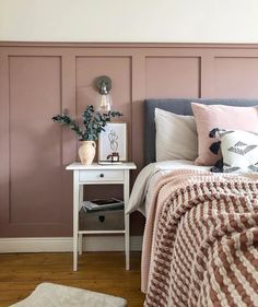 a bedroom with pink walls and white bedding, pillows and blankets on the bed