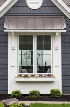 a house with two windows and flowers in the window boxes