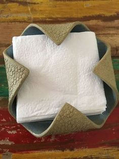 a napkin holder made out of leather with two folded white towels in the middle and one folded on top