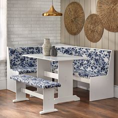 a white table with blue and white patterned bench seats next to a vase on top of it