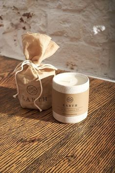 a white candle sitting on top of a wooden table next to a brown paper bag