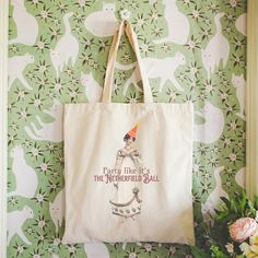 a tote bag hanging on a wall with flowers in the background and an image of a party like it's the netherfield ball