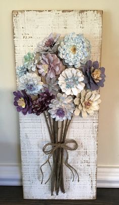 a bunch of flowers are tied to a white board with a brown ribbon on it