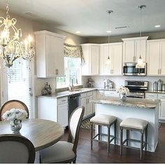 a kitchen filled with lots of white furniture