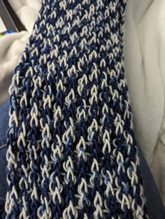 a blue and white knitted tie laying on top of a person's lap