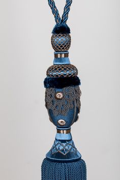 a blue vase with an intricate design on it's side and a tassel hanging from the top