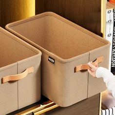 two brown storage bins with handles on top of a bookshelf filled with books