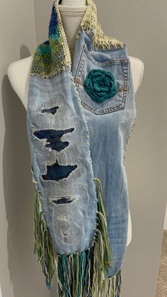 a white mannequin wearing a blue jean vest with green accents and fringes