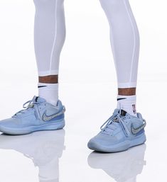 the legs and ankles of a person wearing blue sneakers with white socks, standing on a reflective surface