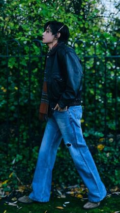 a man in jeans and a leather jacket is walking