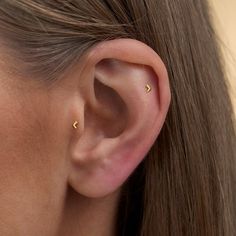 a close up of a person's ear with small gold studs on it