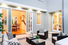 an outdoor living room with couches and tables in front of glass doors that lead into the dining area