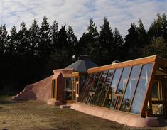 an unusual house made out of concrete and glass with trees in the backgroud