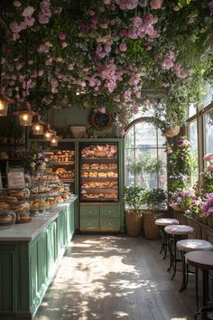 the inside of a bakery with lots of flowers hanging from it's ceiling and pastries on display