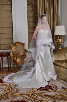 a woman in a white wedding dress standing next to a chair with a veil on her head