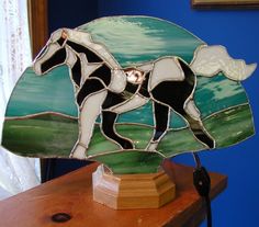 a stained glass horse lamp sitting on top of a wooden table