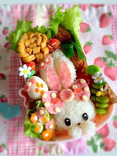 a plate filled with rice and vegetables covered in miniature food items on top of a table cloth