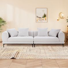 a white couch sitting on top of a wooden floor next to a potted plant