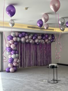 purple and silver balloons are hanging from the ceiling