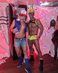 two men in costumes standing next to each other on a wooden floor with pink lights behind them