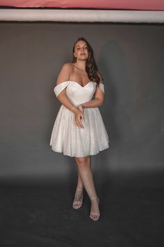 a woman in a short white dress posing for a photo with her hands on her hips