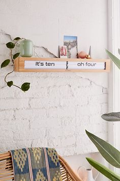 a wooden shelf with some books on top of it next to a potted plant