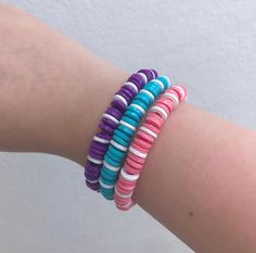 a woman's arm with four bracelets on it, one is multicolored