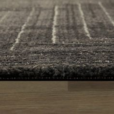 an area rug with white lines on top of it and a wooden floor in the background