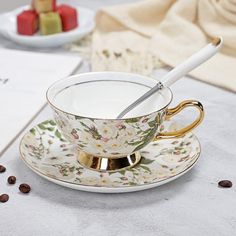 a tea cup and saucer on a table with coffee beans