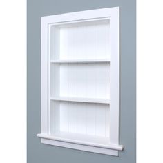 a white book shelf with three shelves on each side and one in the middle, against a blue wall