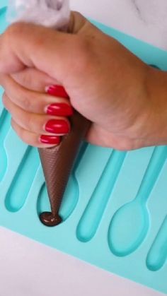 a woman's hand holding an ice cream cone with red nail polish on it