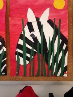 two paintings of zebras are hanging on the wall in front of a red background