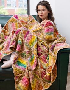 a woman sitting on a couch under a colorful blanket