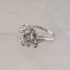 Vintage 18K White Gold 1ct Diamond Cocktail Ring, 1/4 ct center brilliant cut, round diamond 12 diamond single cut surround in an asymmetrical floral design, H SI 1,.5 inch across, Ring size 7.75, Circa 1960, 5.2 grams SKU# BB331R10 This listing contains photographs of the actual item you will receive. Our items are in excellent condition with little or no signs of wear and many are one of a kind pre-owned estate finds. Please look closely at the pictures in this listing as they are part of the Classic White Gold Flower Ring With Rose Cut Diamonds, Classic Flower Ring With Single Cut Diamonds, Classic Flower Ring With Single Cut Diamonds For Anniversary, Formal Single Cut Diamond Flower Ring, Classic Flower Ring With Rose Cut Diamonds, Classic Diamond Flower Ring For Weddings, Formal Flower Ring With Brilliant Cut Diamond, Formal Diamond Flower Ring With Brilliant Cut, Anniversary Rose Cut Diamond Cluster Ring