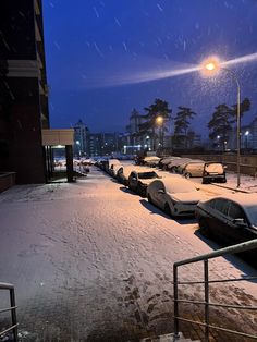 cars are parked in the snow at night