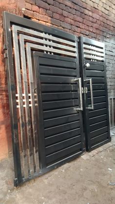 two black gates are open in front of a brick wall