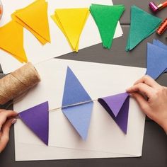 someone is making paper triangles out of colored construction paper and twine on the table