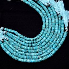 turquoise beads with tassels are arranged on a black surface