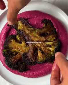 a plate with some broccoli on it and someone pointing at the food in the bowl